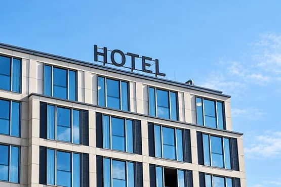 Façade d’un hôtel moderne aux grandes fenêtres, avec l’enseigne « HOTEL » sur le toit.