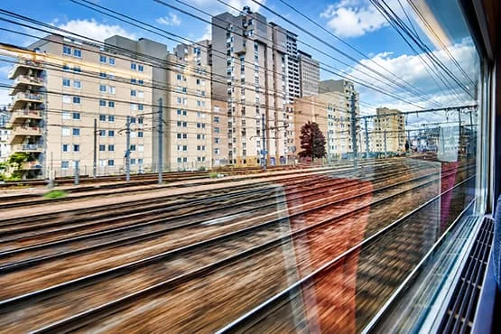 Voies ferrées et immeubles vus à travers la fenêtre d’un train.